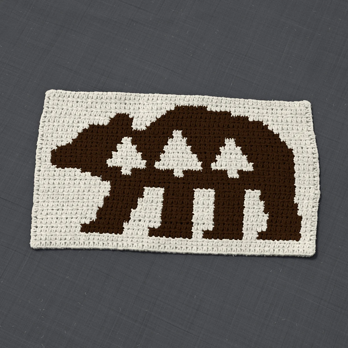 A panel in single crochet, 16.9 by 9.9 inches: a walking bear with three pine trees in dark brown on a cream ground, 55 stitches by 37 rows