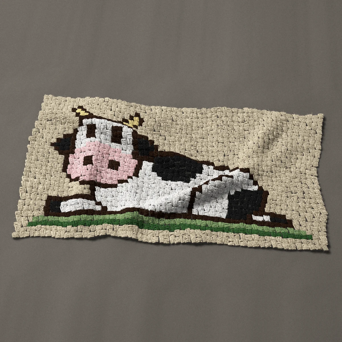 A panel worked corner to corner, 42 by 23¼ inches: Black and white Holstein cow lying down in the grass, 56 by 31 blocks