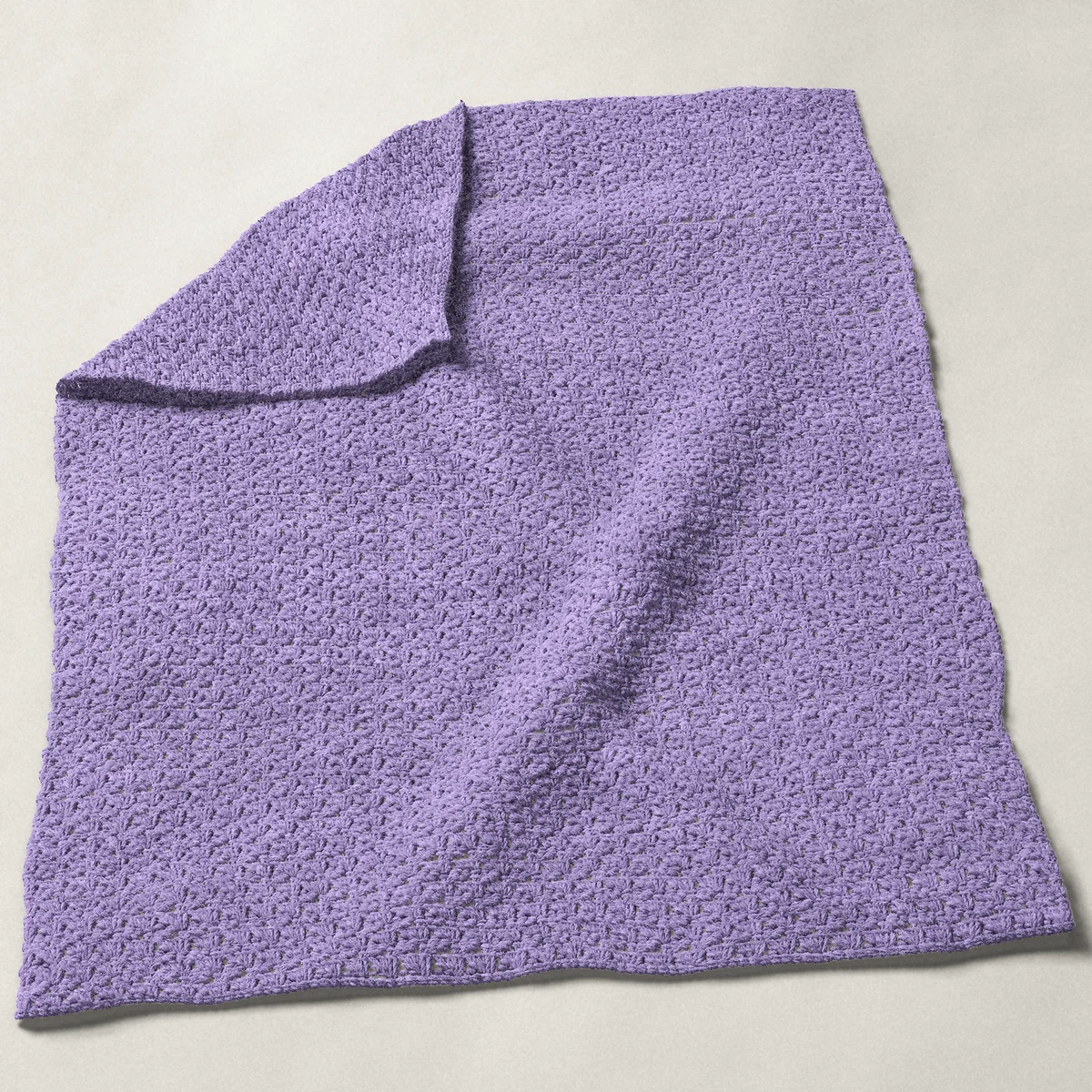 A baby blanket in blanket stitch, 31¾ by 40 inches, spread out with a corner turned over