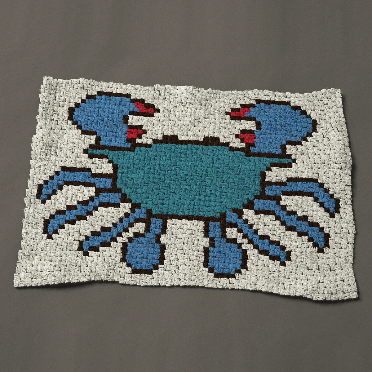 A baby blanket worked corner to corner, 45½ by 31½ inches: Blue crab seen from above with red-tipped claws, 61 by 42 blocks
