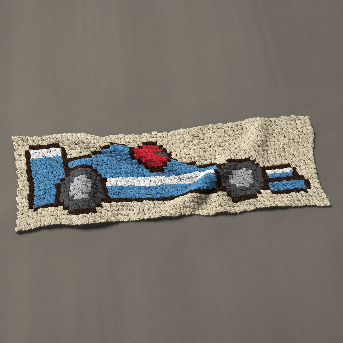 A panel worked corner to corner, 46½ by 16½ inches: Blue race car with a white stripe and red helmet, 62 by 22 blocks