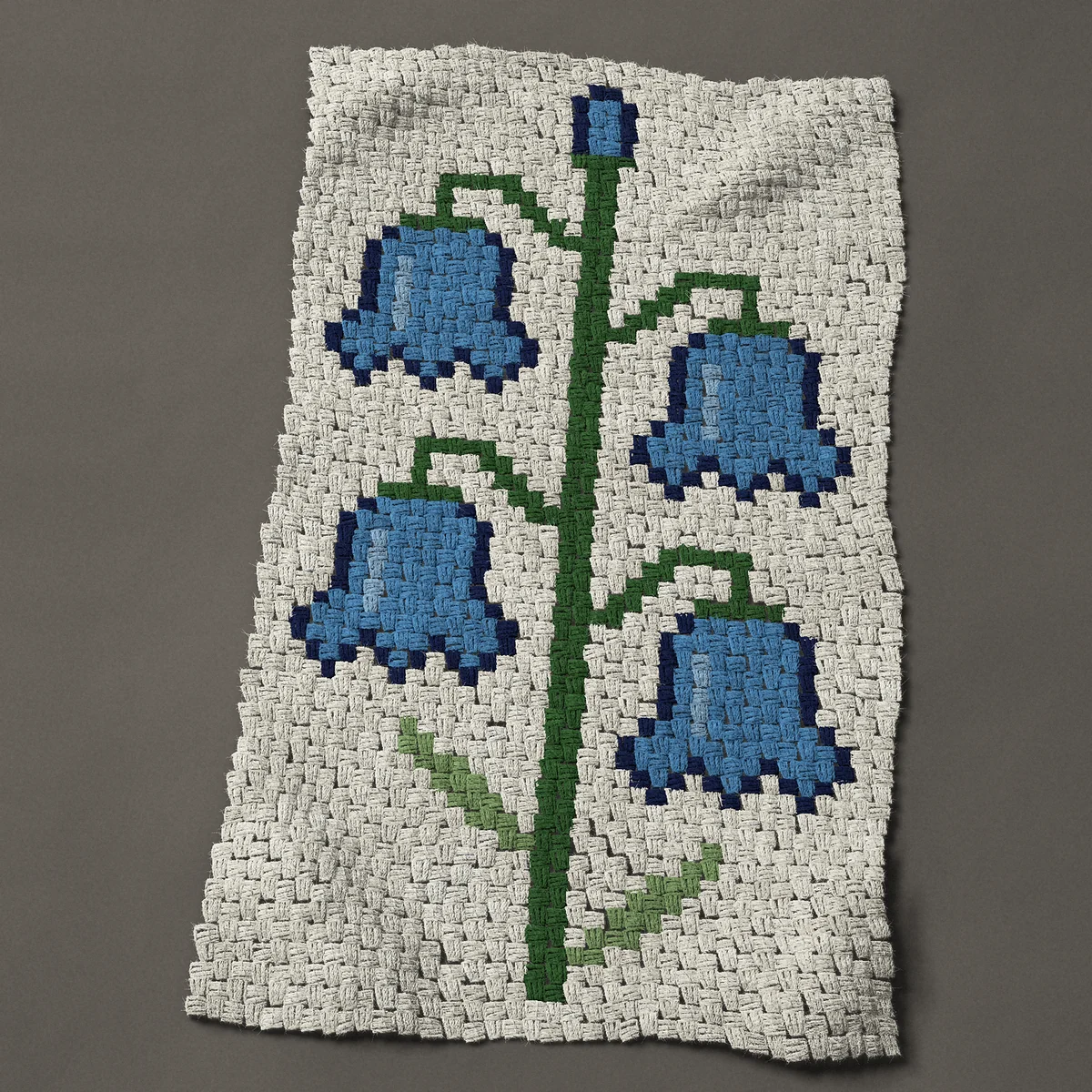 A baby blanket worked corner to corner, 27 by 45½ inches: Bluebell stem with four nodding blue flowers and a bud, 36 by 61 blocks