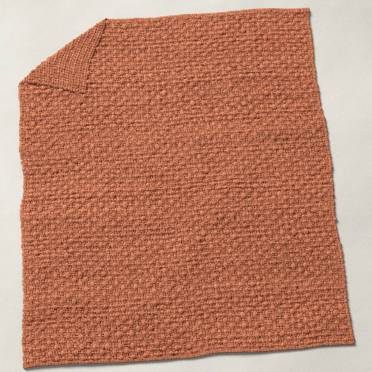 A baby blanket in bobble stitch, 32¼ by 40 inches, spread out with a corner turned over, showing the cloth's other side