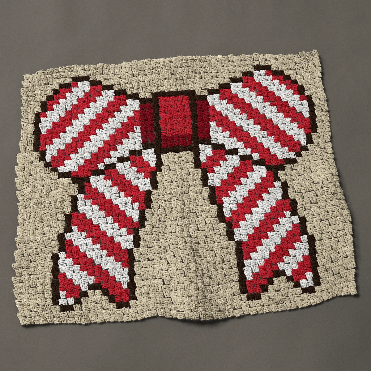 A baby blanket worked corner to corner, 36¾ by 32¼ inches: Candy cane striped Christmas bow in red and white, 49 by 43 blocks