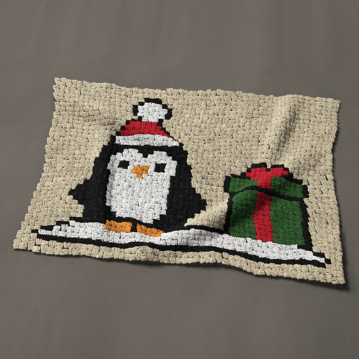 A baby blanket worked corner to corner, 41 by 30 inches: Christmas penguin in a Santa hat with a gift, 55 by 40 blocks