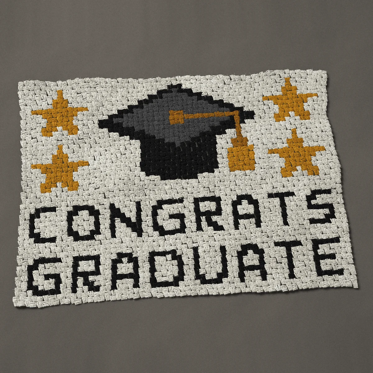 A baby blanket worked corner to corner, 45½ by 34½ inches: Congrats Graduate with a graduation cap and gold stars, 61 by 46 blocks
