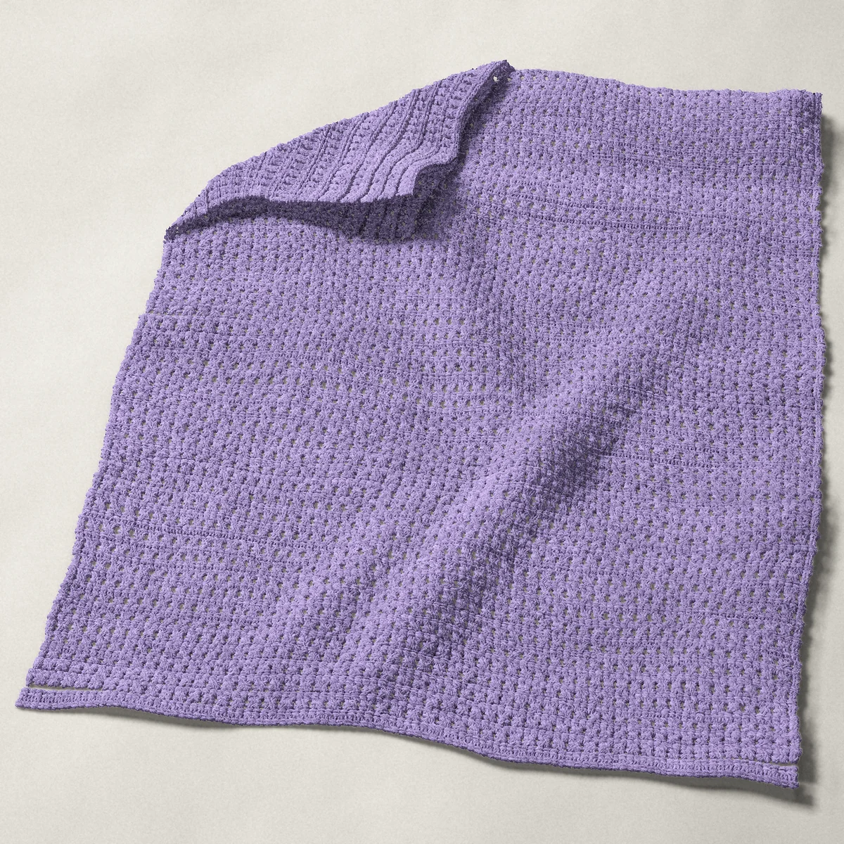 A baby blanket in crossed double crochet, 32 by 40 inches, spread out with a corner turned over