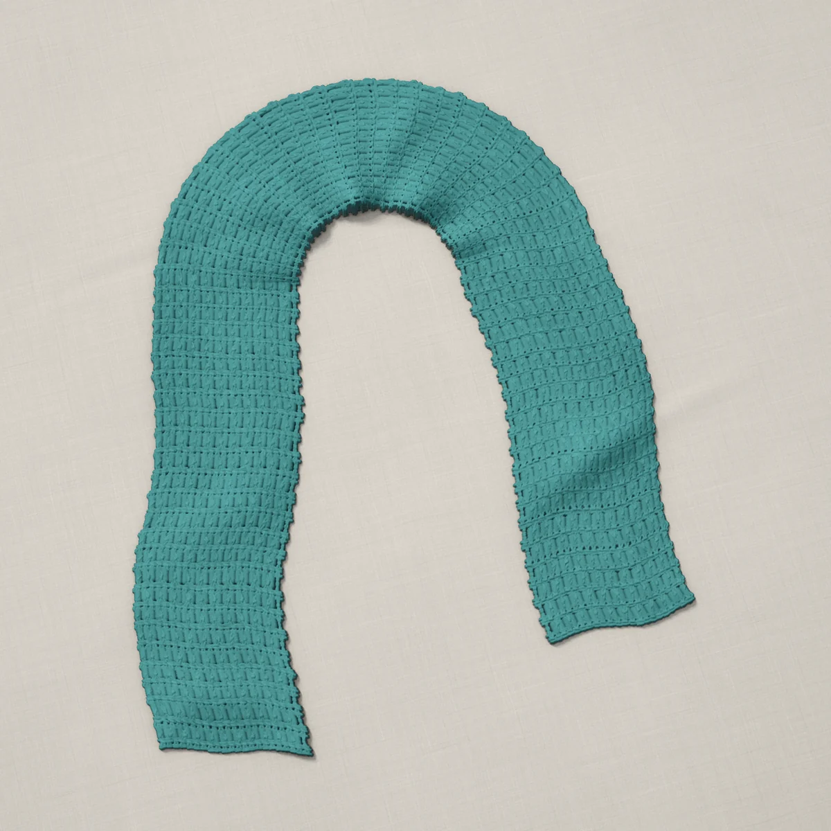 A scarf in crossed double crochet, 6¾ by 60¼ inches, lying in a loose bend