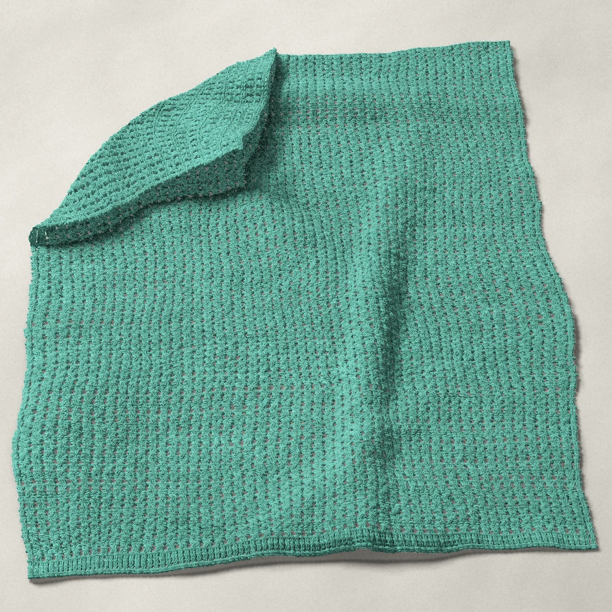 A baby blanket in crossed double crochet in every row, 32 by 40 inches, spread out with a corner turned over