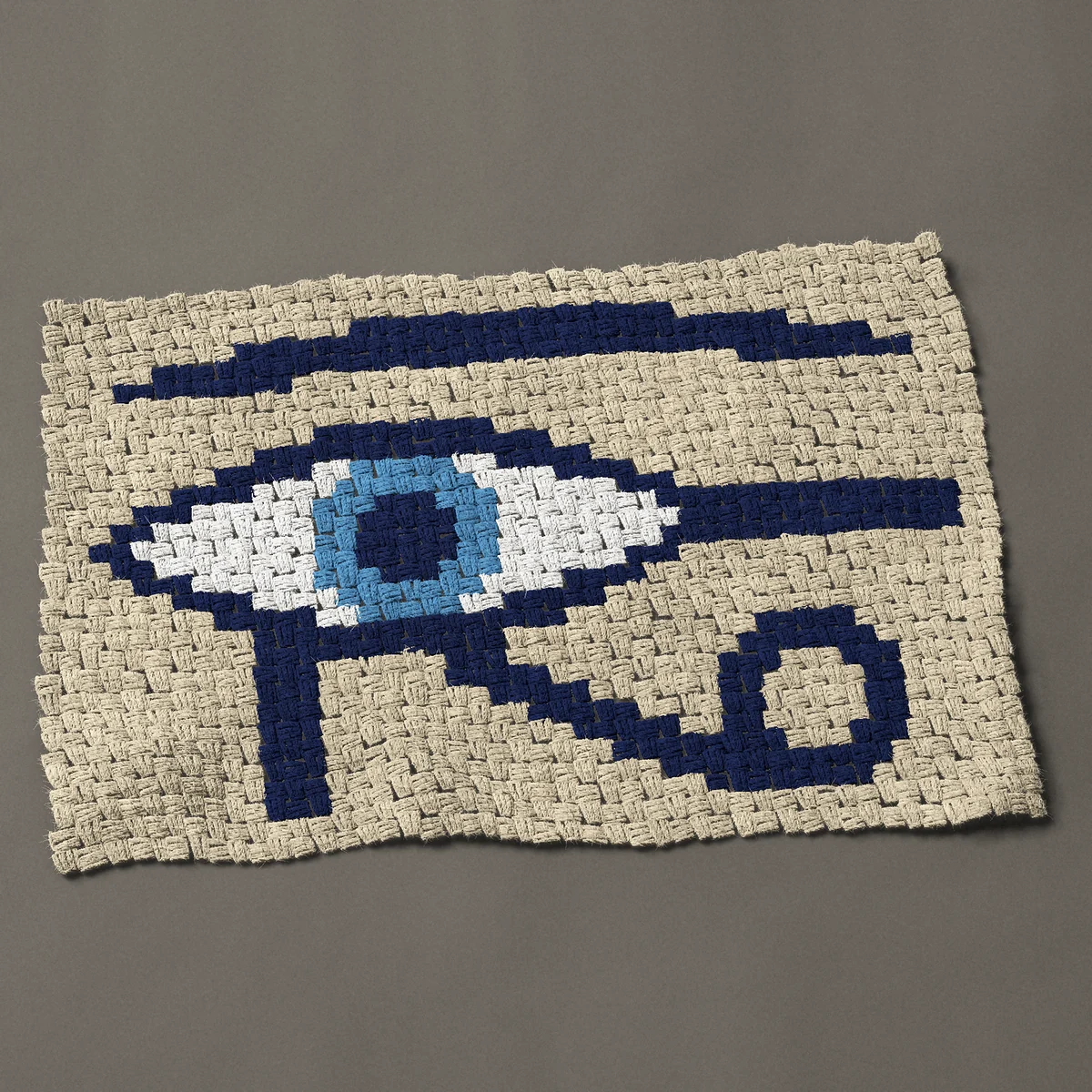 A panel worked corner to corner, 35¼ by 23¼ inches: Eye of Horus: Egyptian eye symbol in navy blue, 47 by 31 blocks