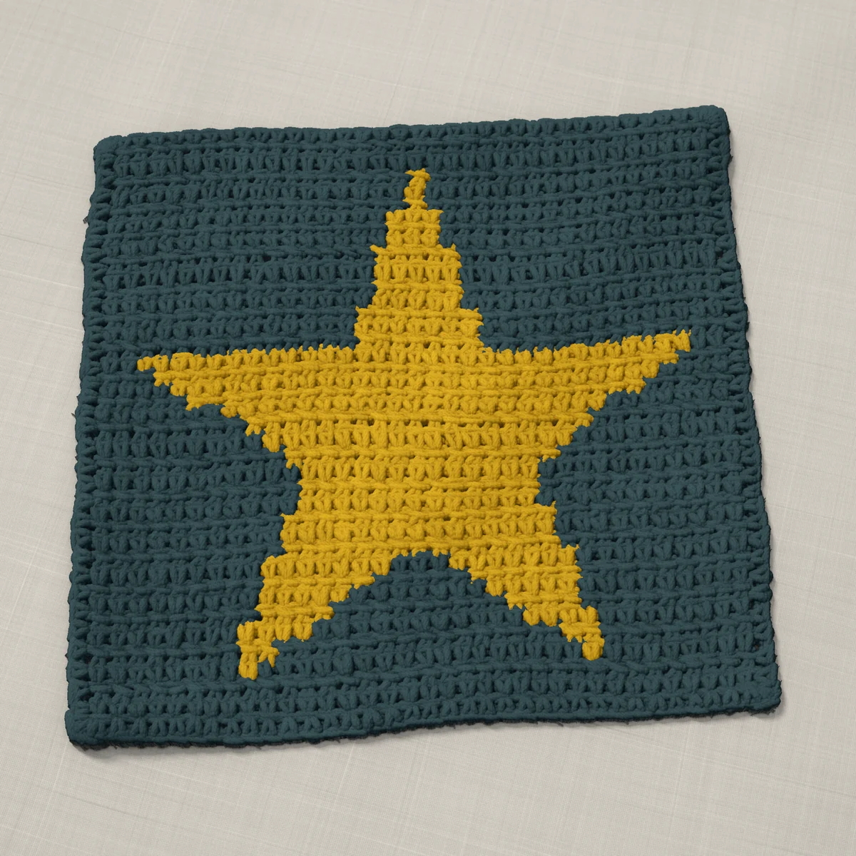 A washcloth in single crochet, 10.8 by 10.1 inches: a five-point star in gold on a slate gray ground, 35 stitches by 38 rows