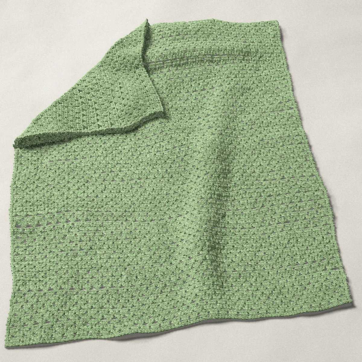 A baby blanket in granny stripe, 32 by 40 inches, spread out with a corner turned over