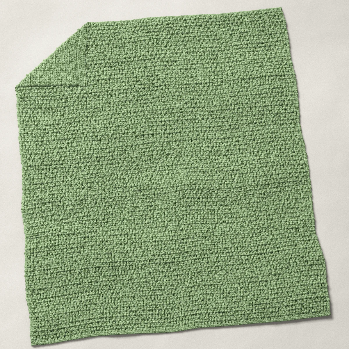 A baby blanket in granule stitch, 32¼ by 39¾ inches, spread out with a corner turned over, showing the cloth's other side