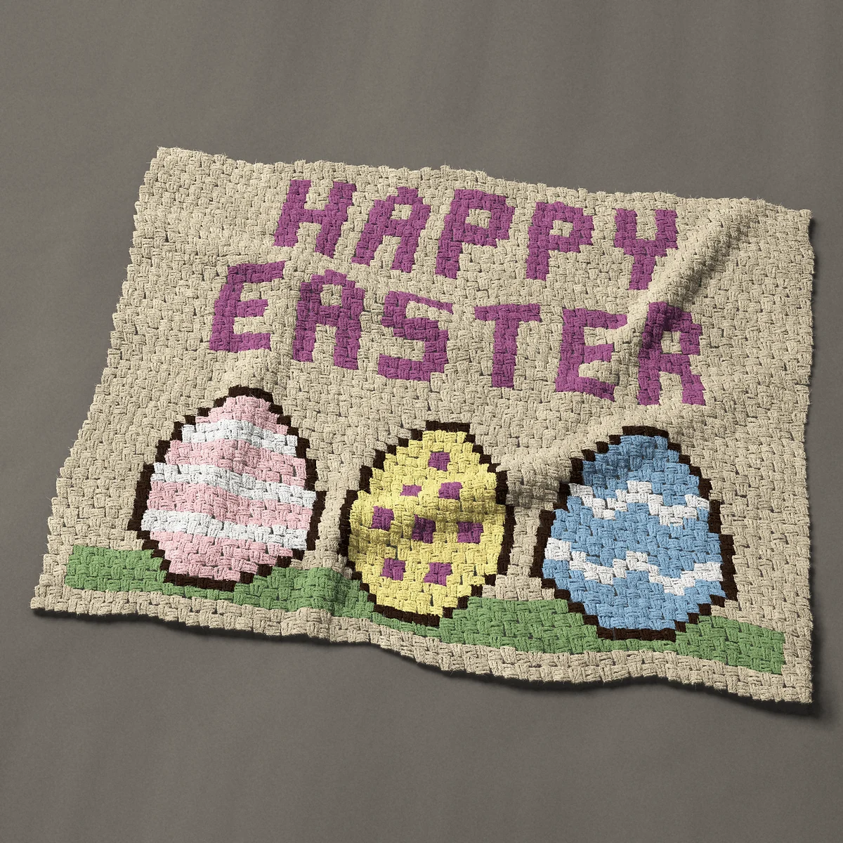A baby blanket worked corner to corner, 48 by 39½ inches: Happy Easter lettering over three decorated Easter eggs, 64 by 53 blocks