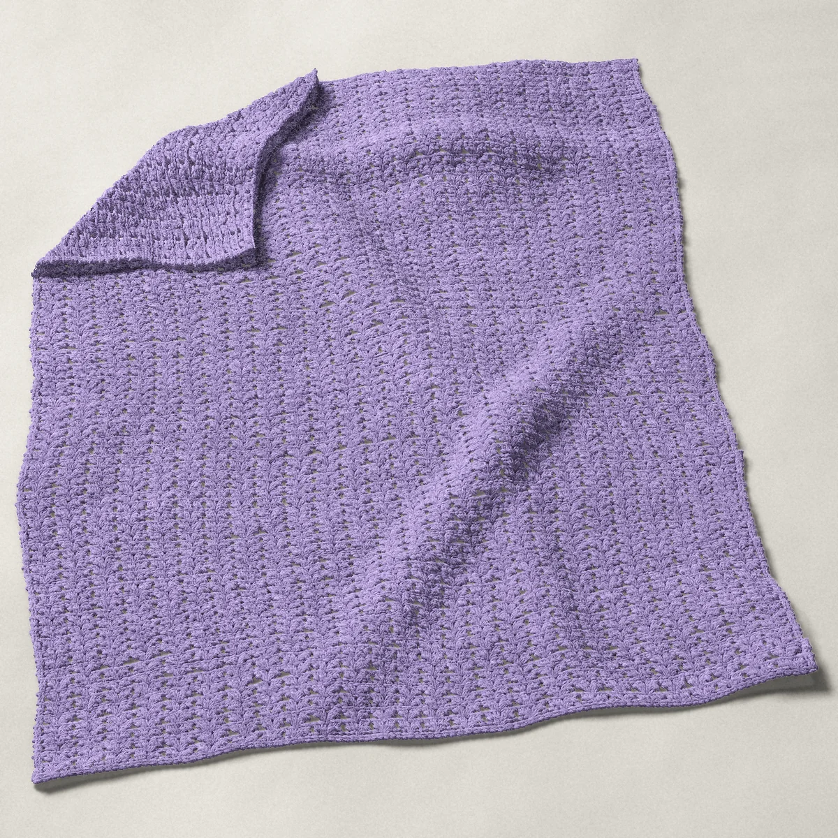 A baby blanket in iris stitch, 32¼ by 40 inches, spread out with a corner turned over