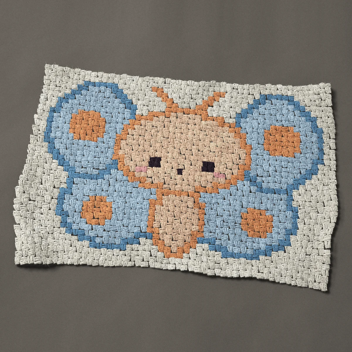 A baby blanket worked corner to corner, 38 by 27 inches: Kawaii butterfly in blue with orange spots, 51 by 36 blocks