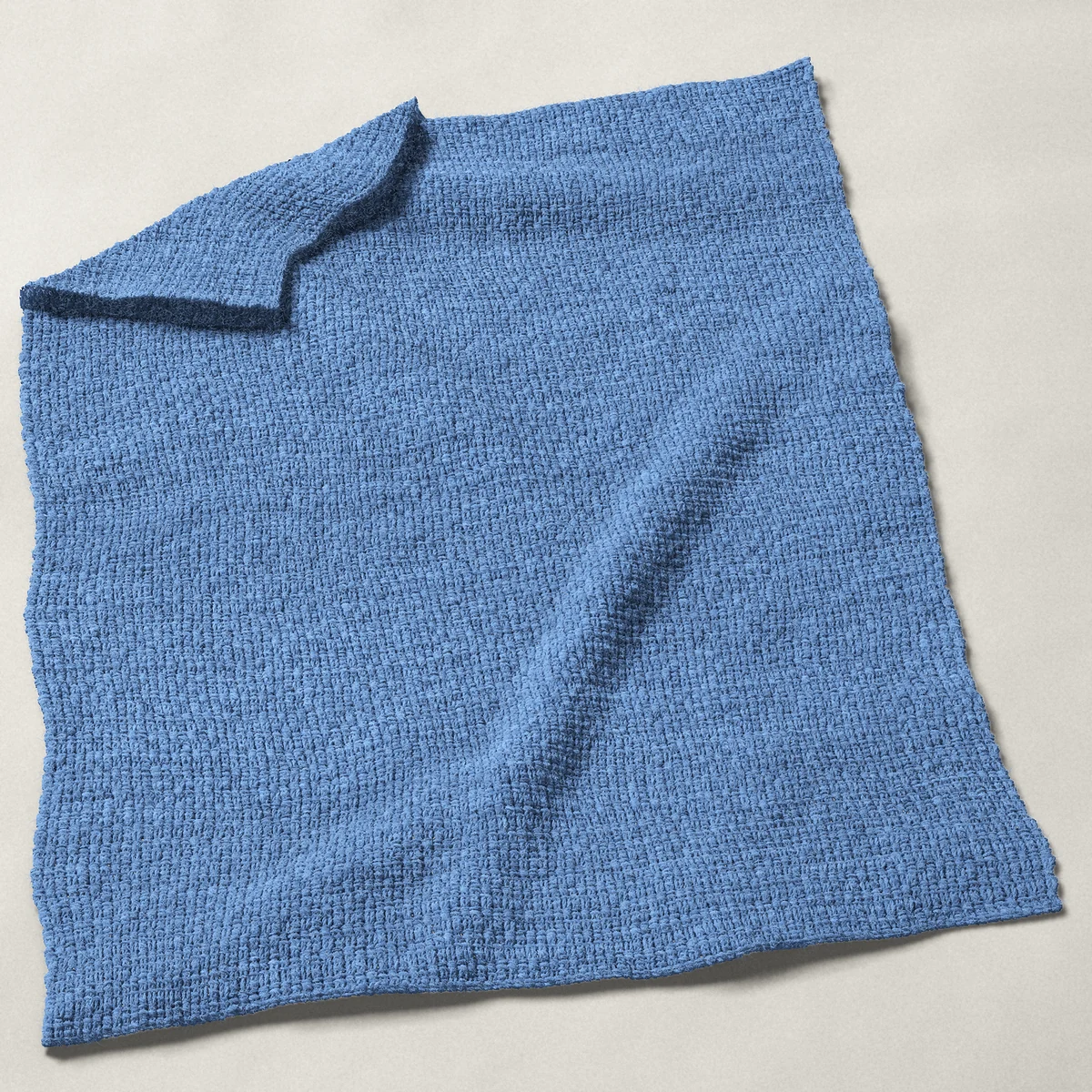 A baby blanket in lemon peel stitch, 32 by 40 inches, spread out with a corner turned over