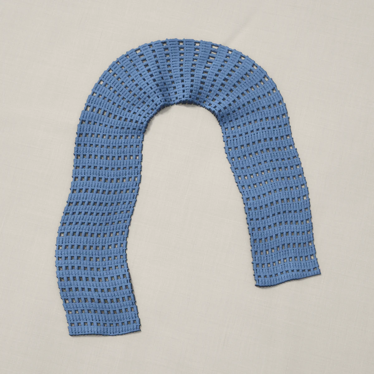 A scarf in mesh and double crochet rows, 7.1 by 60 inches, lying in a loose bend