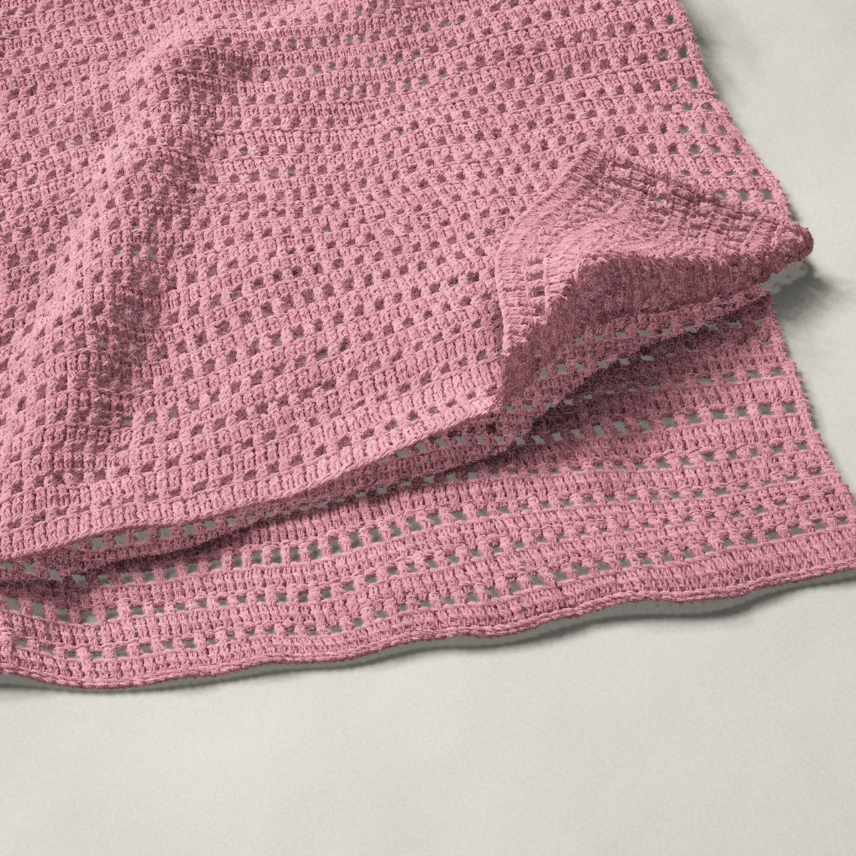 A throw in mesh and double crochet rows, 50¼ by 60 inches, folded in half with a corner turned back