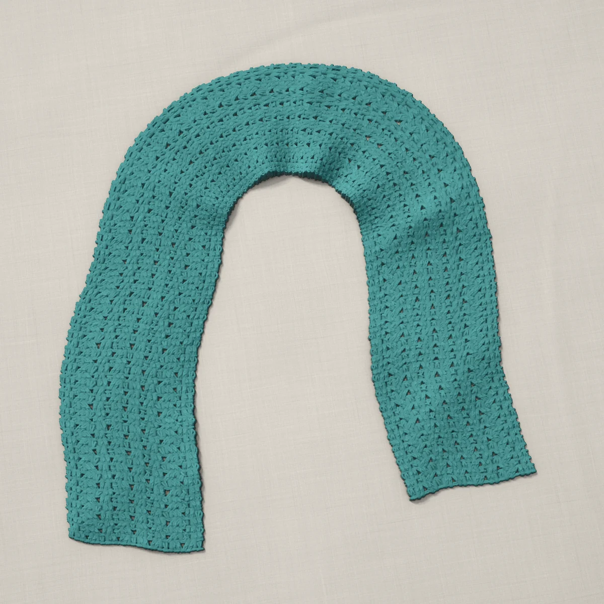 A scarf in open shell stitch, 7.7 by 60 inches, lying in a loose bend
