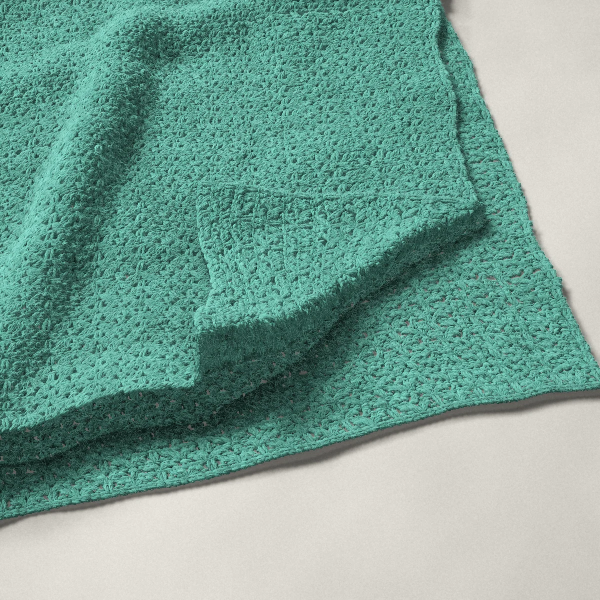 A throw in open shell stitch, 50¼ by 60 inches, folded in half with a corner turned back