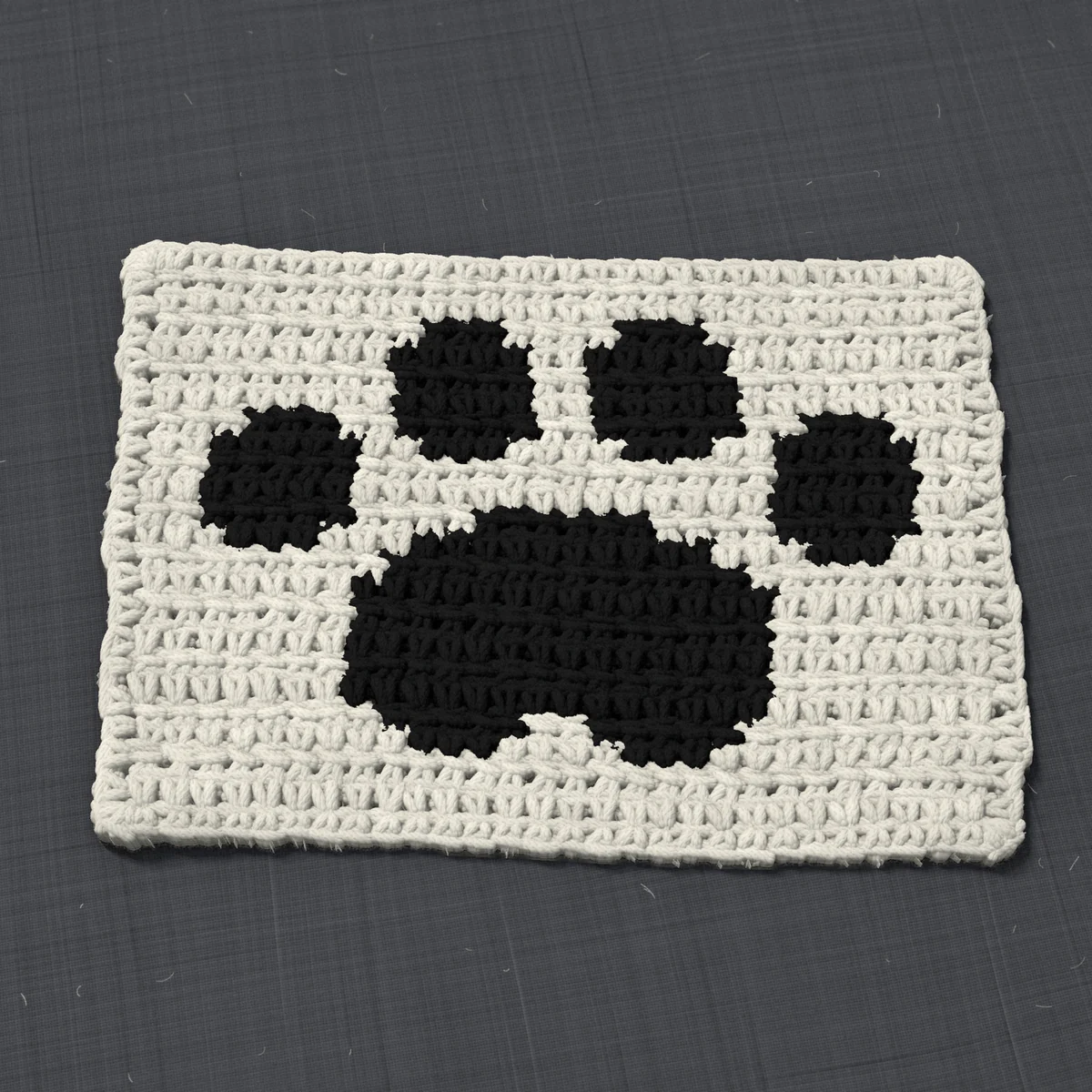 A panel in single crochet, 8.6 by 5.9 inches: a paw print in black on a cream ground, 28 stitches by 22 rows