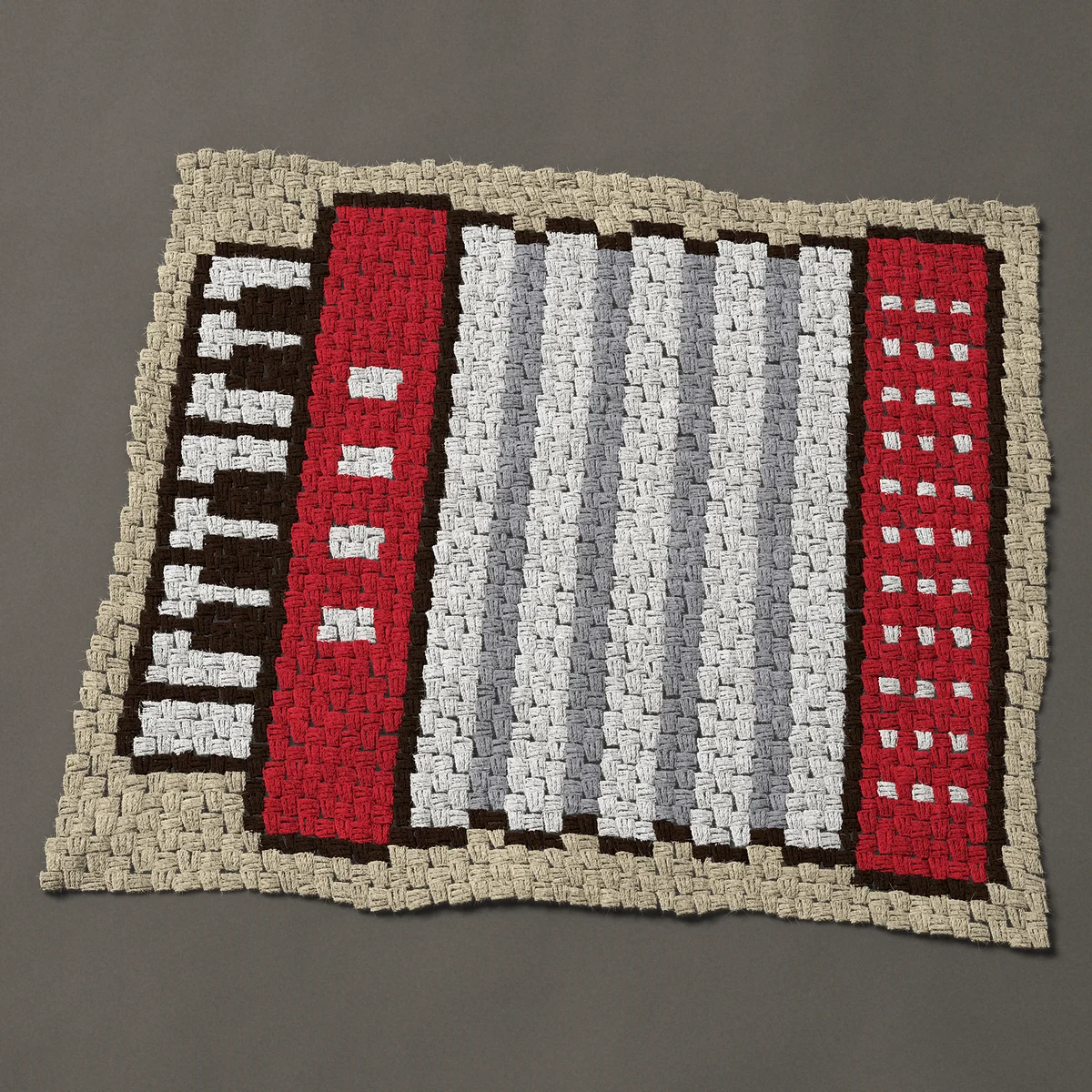 A baby blanket worked corner to corner, 39 by 33¾ inches: Red accordion with piano keys and pleated bellows, 52 by 45 blocks