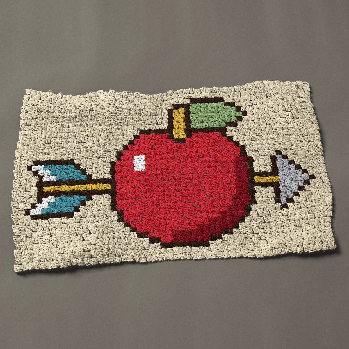 A panel worked corner to corner, 39 by 24 inches: Red apple shot through with an arrow, 52 by 32 blocks