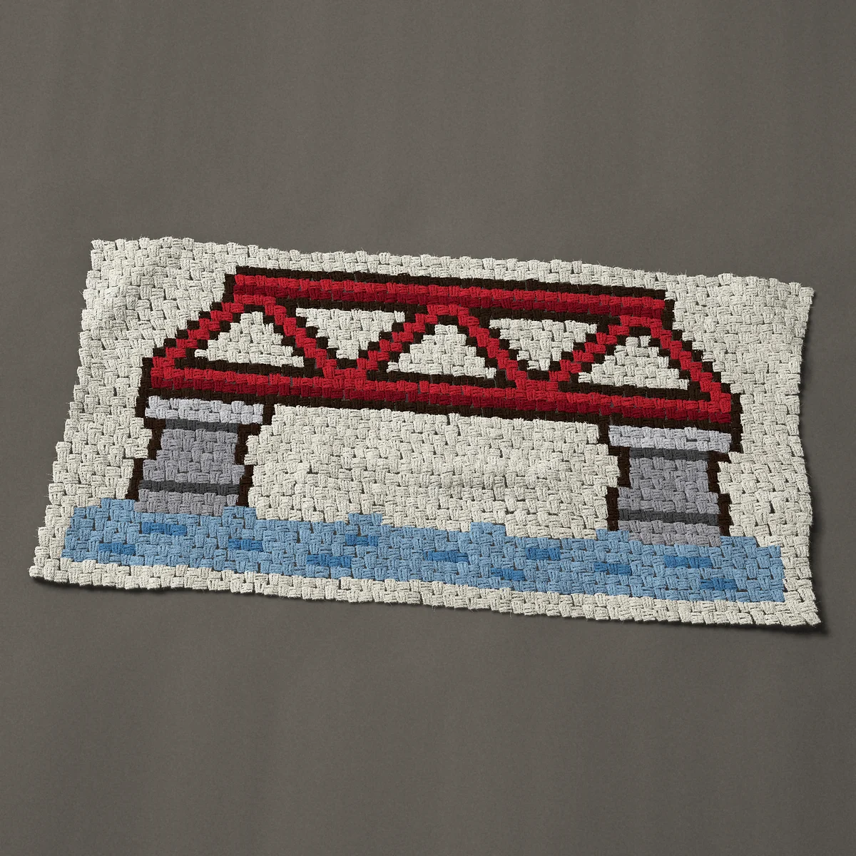 A baby blanket worked corner to corner, 49½ by 25½ inches: Red steel truss bridge on stone piers over a river, 66 by 34 blocks