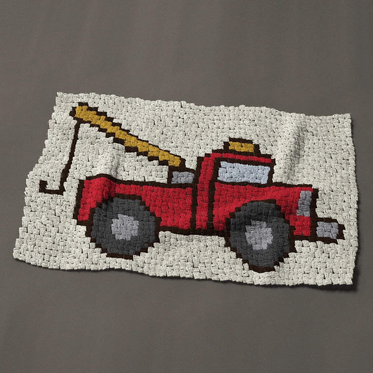 A baby blanket worked corner to corner, 42½ by 27¾ inches: Red tow truck with a yellow boom and hook, 57 by 37 blocks