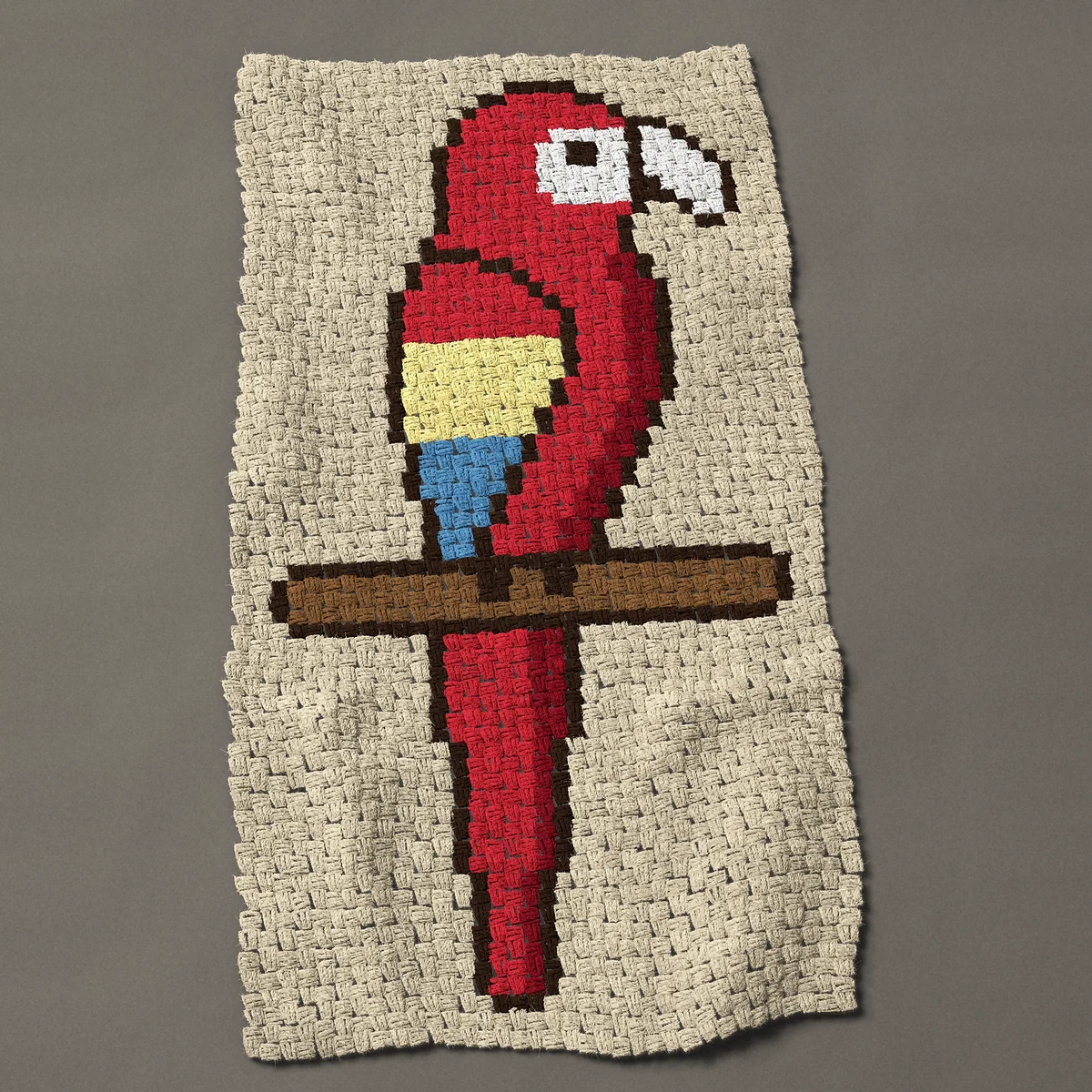 A baby blanket worked corner to corner, 26¼ by 50 inches: Scarlet macaw parrot on a perch with a long red tail, 35 by 67 blocks