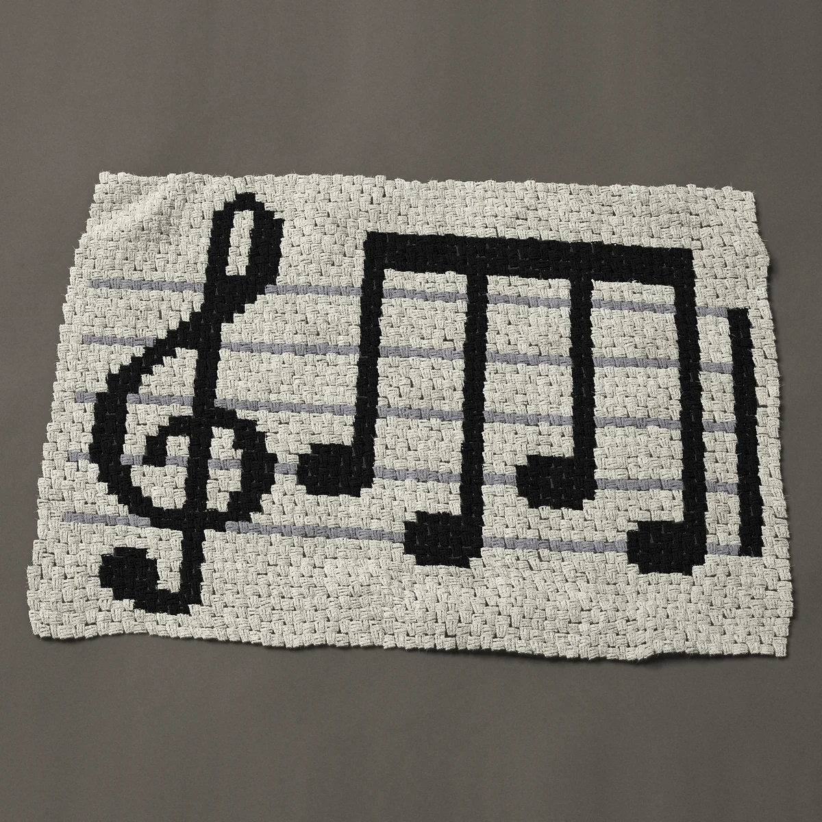 A baby blanket worked corner to corner, 50 by 35¼ inches: Sheet music: treble clef and four notes on a staff, 67 by 47 blocks