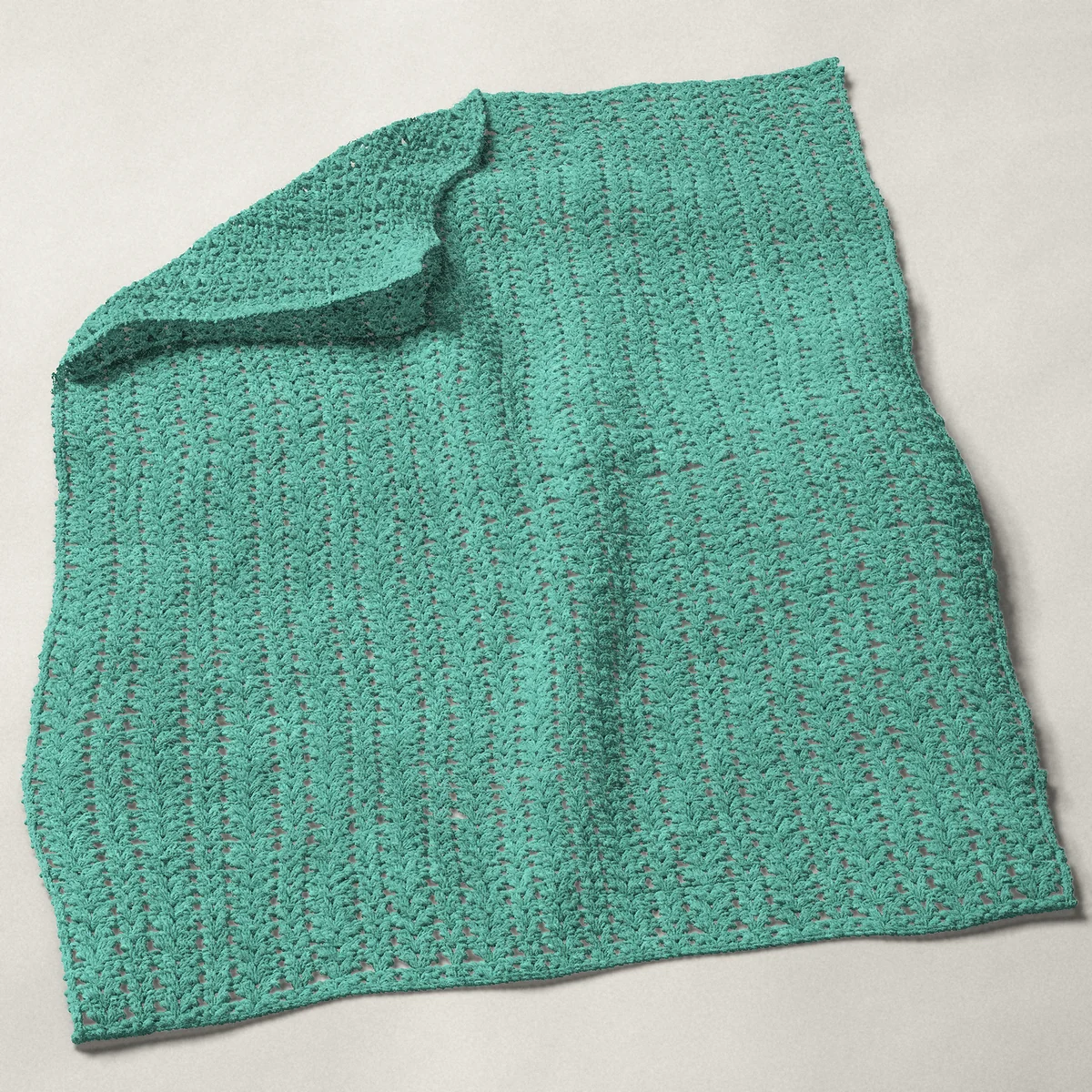 A baby blanket in shell and V-stitch columns, 31¾ by 40 inches, spread out with a corner turned over