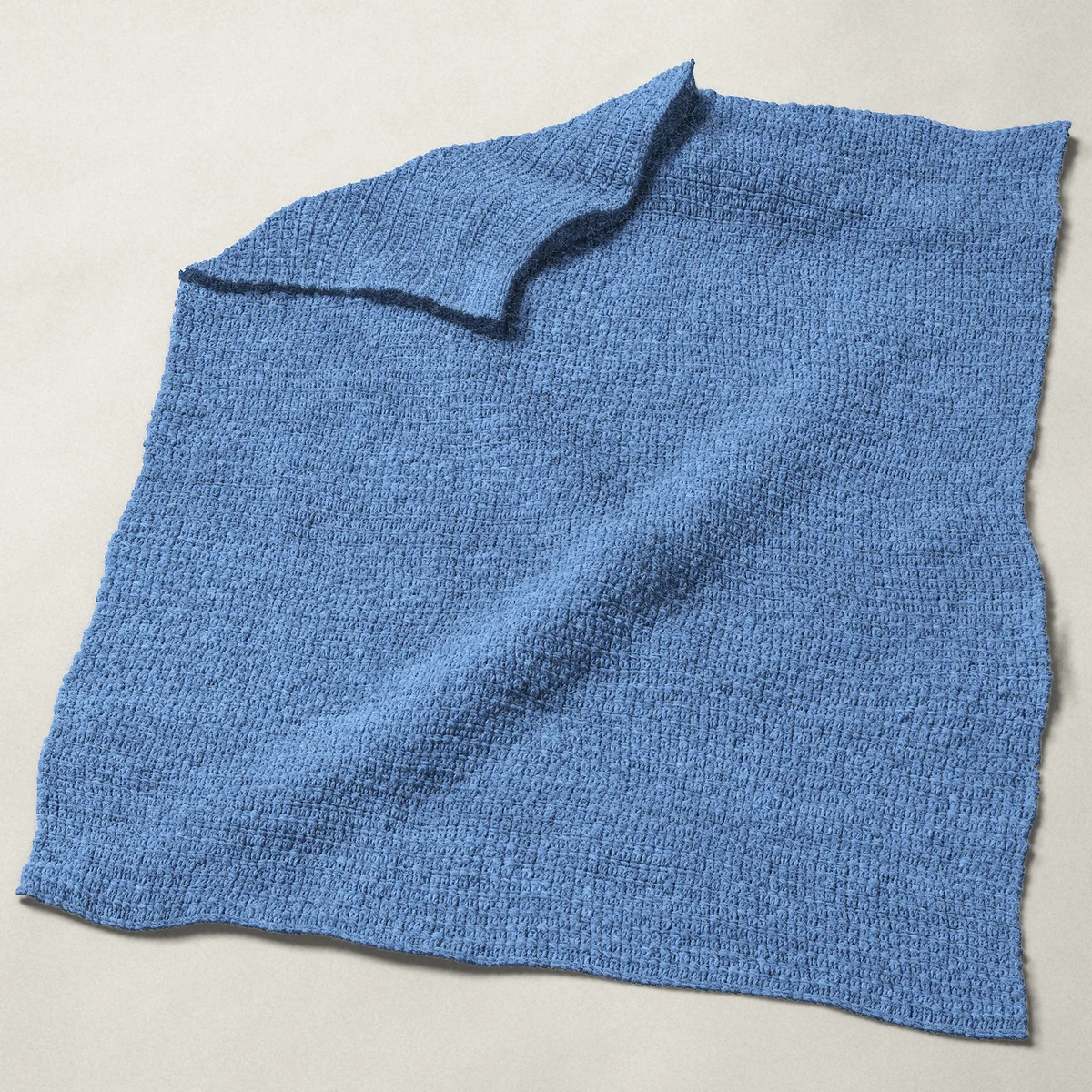 A baby blanket in single crochet, 32 by 40 inches, spread out with a corner turned over