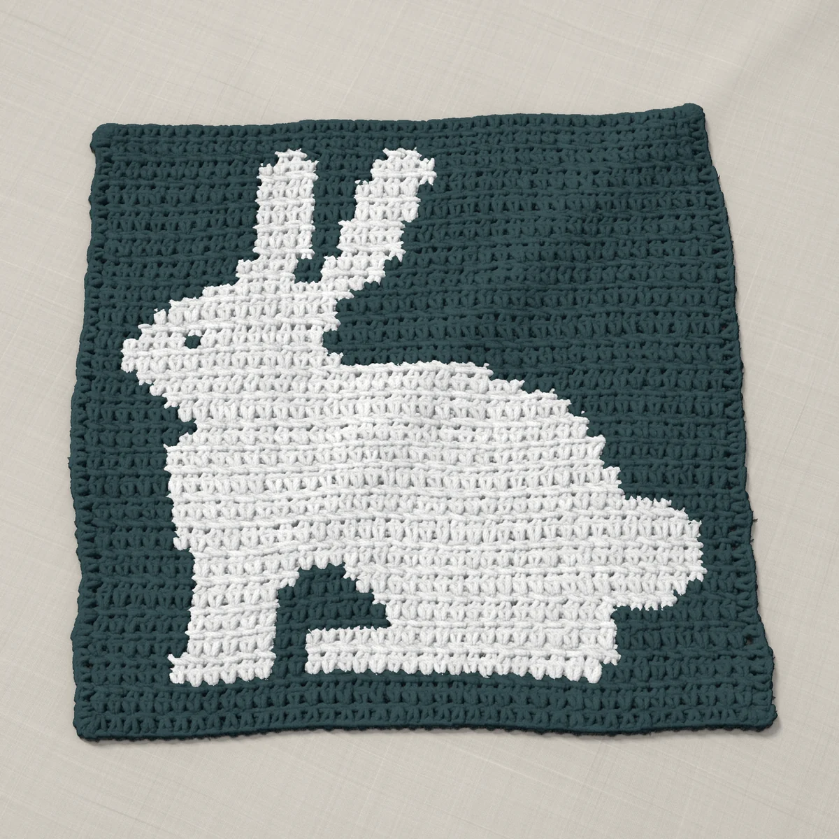 A pillow front in single crochet, 12.3 by 12.3 inches: a rabbit in white on a slate gray ground, 40 stitches by 46 rows