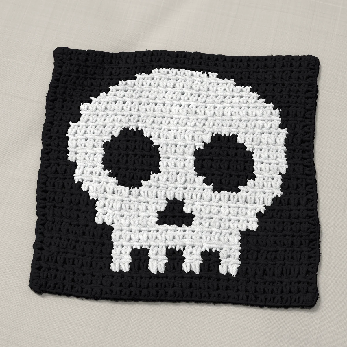 A washcloth in single crochet, 9.2 by 8.8 inches: a skull in white on a black ground, 30 stitches by 33 rows