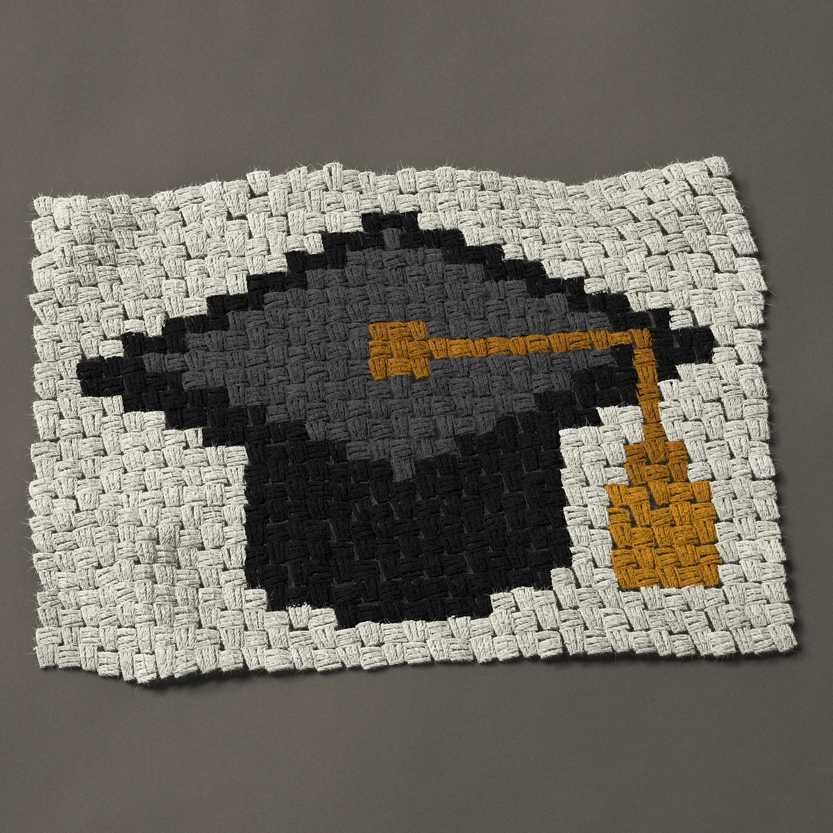 A panel worked corner to corner, 26¼ by 18¾ inches: Graduation cap with a gold tassel, 35 by 25 blocks