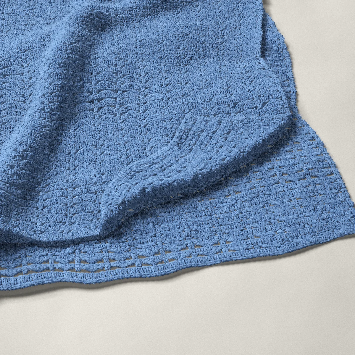 A throw in shell and single crochet rows, 50¼ by 60 inches, folded in half with a corner turned back