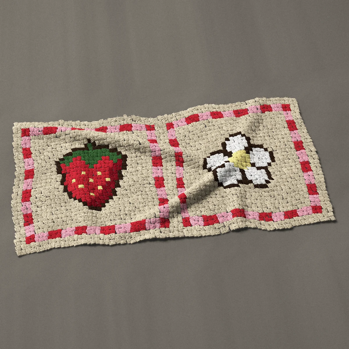 A baby blanket worked corner to corner, 51½ by 26¼ inches: Strawberry and flower in two red checked squares, 69 by 35 blocks