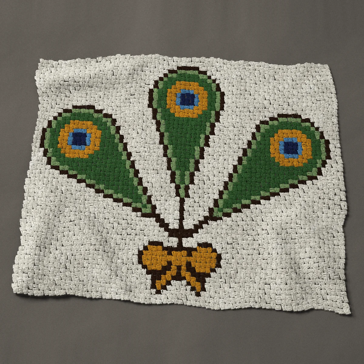 A panel worked corner to corner, 50 by 42½ inches: Three peacock feathers tied with a gold bow, 67 by 57 blocks