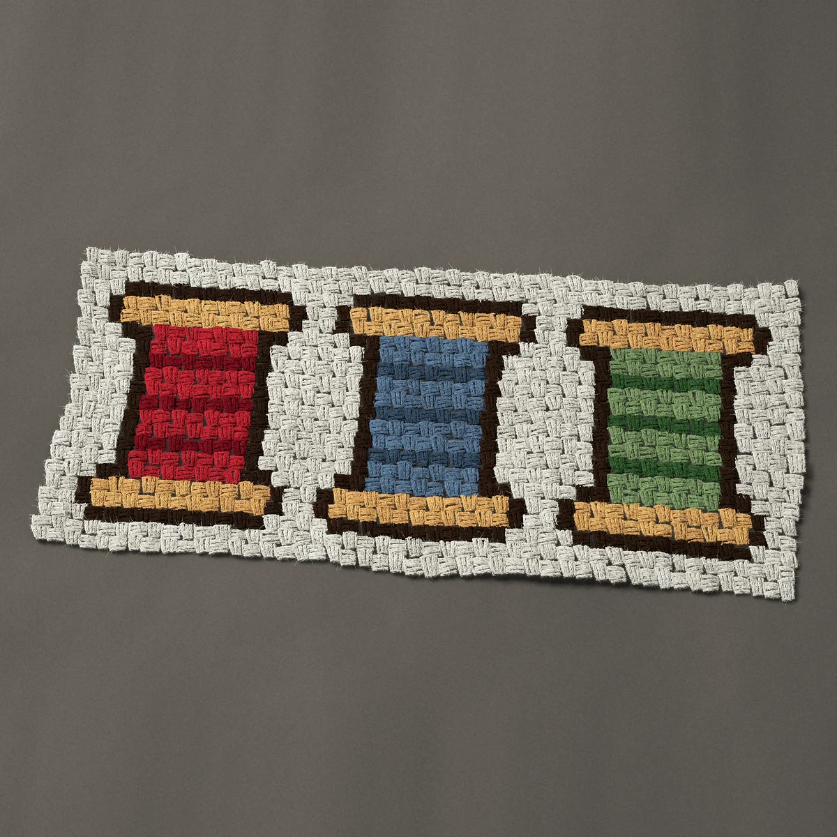A panel worked corner to corner, 35¼ by 15¾ inches: Three wooden thread spools in red, blue and green, 47 by 21 blocks