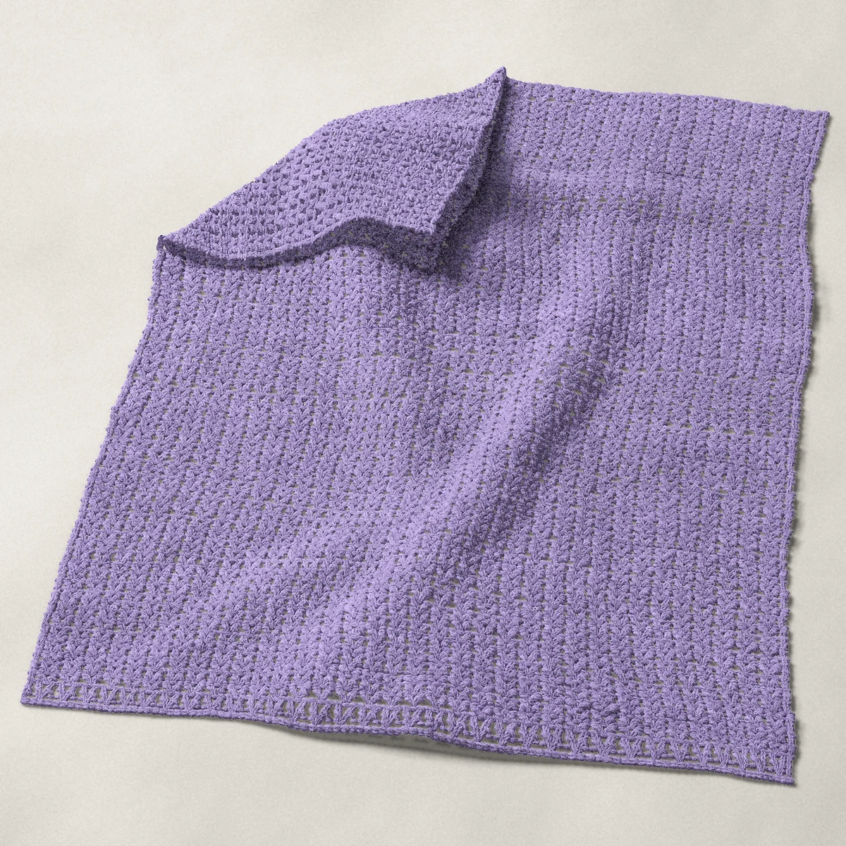 A baby blanket in V-stitch, 32 by 40 inches, spread out with a corner turned over