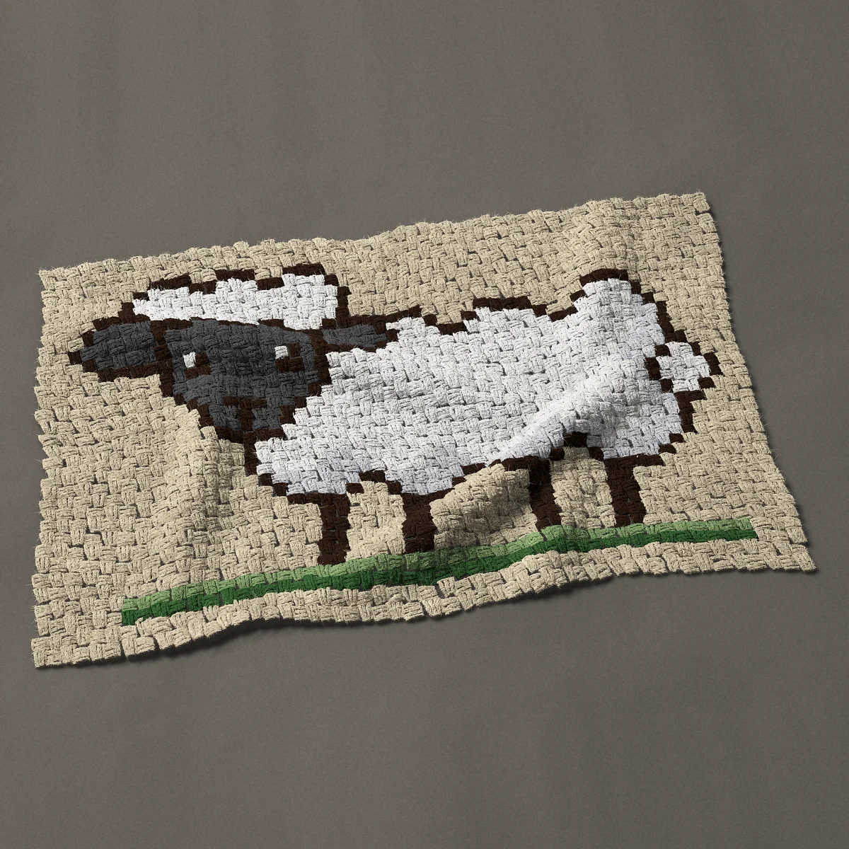 A baby blanket worked corner to corner, 39½ by 25½ inches: Woolly white sheep with a dark face standing on grass, 53 by 34 blocks