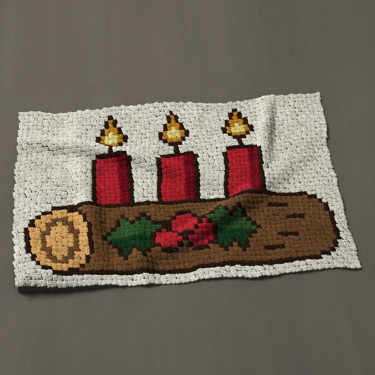 A baby blanket worked corner to corner, 50 by 33¾ inches: Yule log with three lit red candles and holly, 67 by 45 blocks